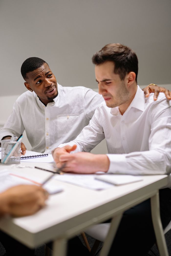 Caring professional comforting a distressed coworker at the office.